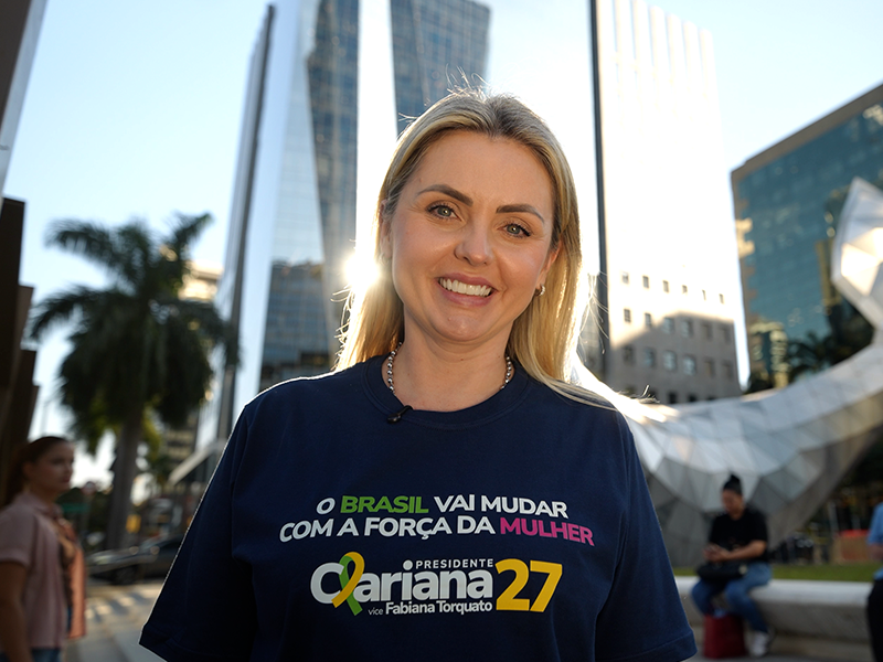 Clariana Barão sorrindo na rua, com camiseta da campanha 27